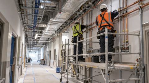 Técnicos con EPP instalando tuberías en una instalación industrial